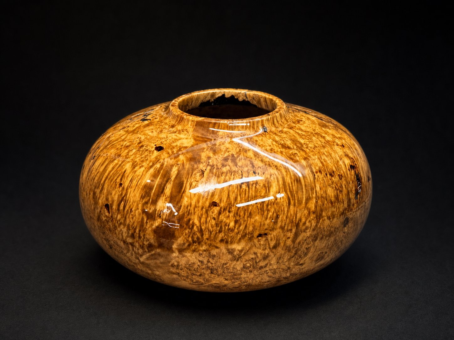 Golden burl hollow-form vessel on studio black.