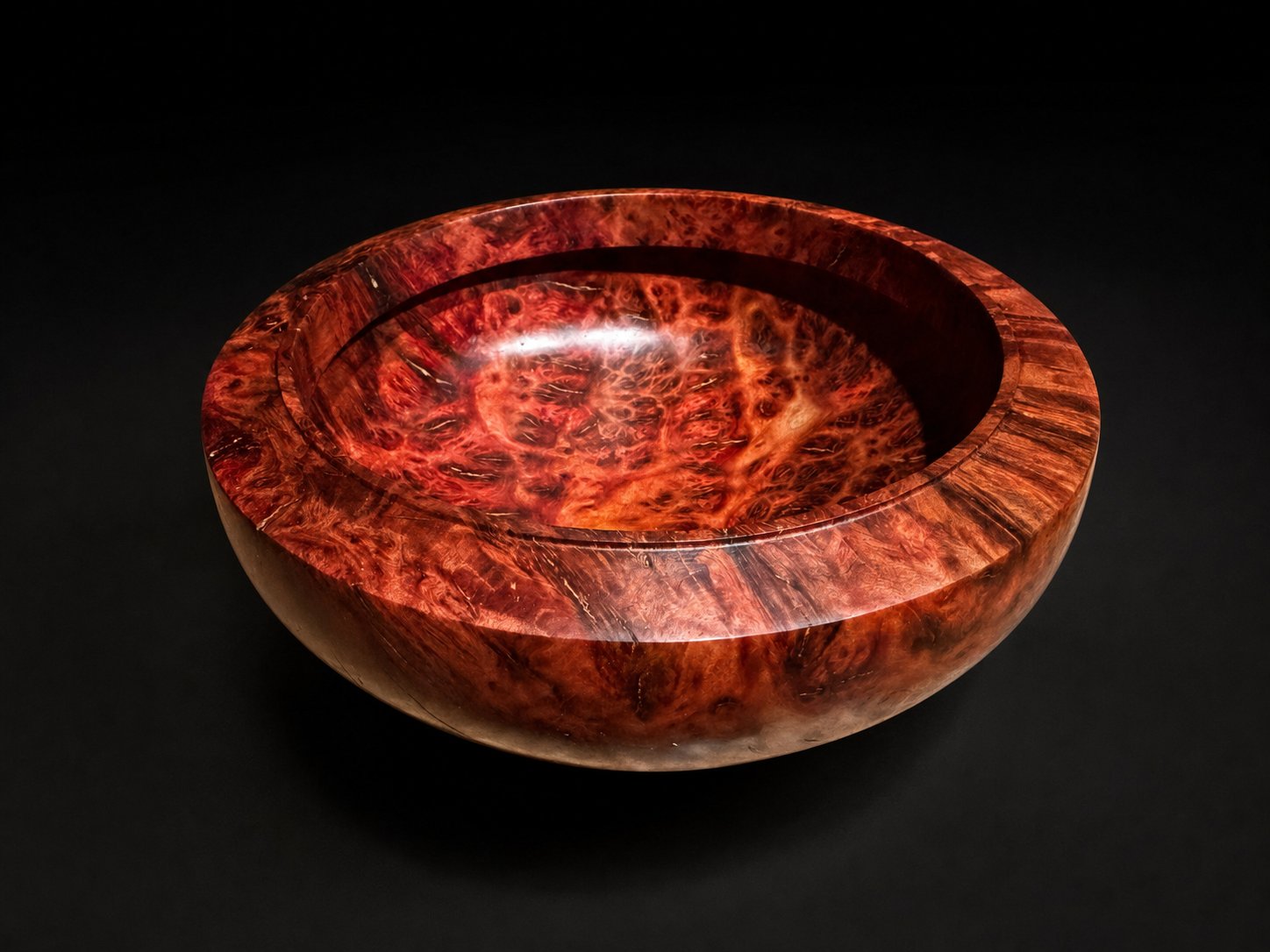 Deep red burl bowl with a wide rim, on studio black.