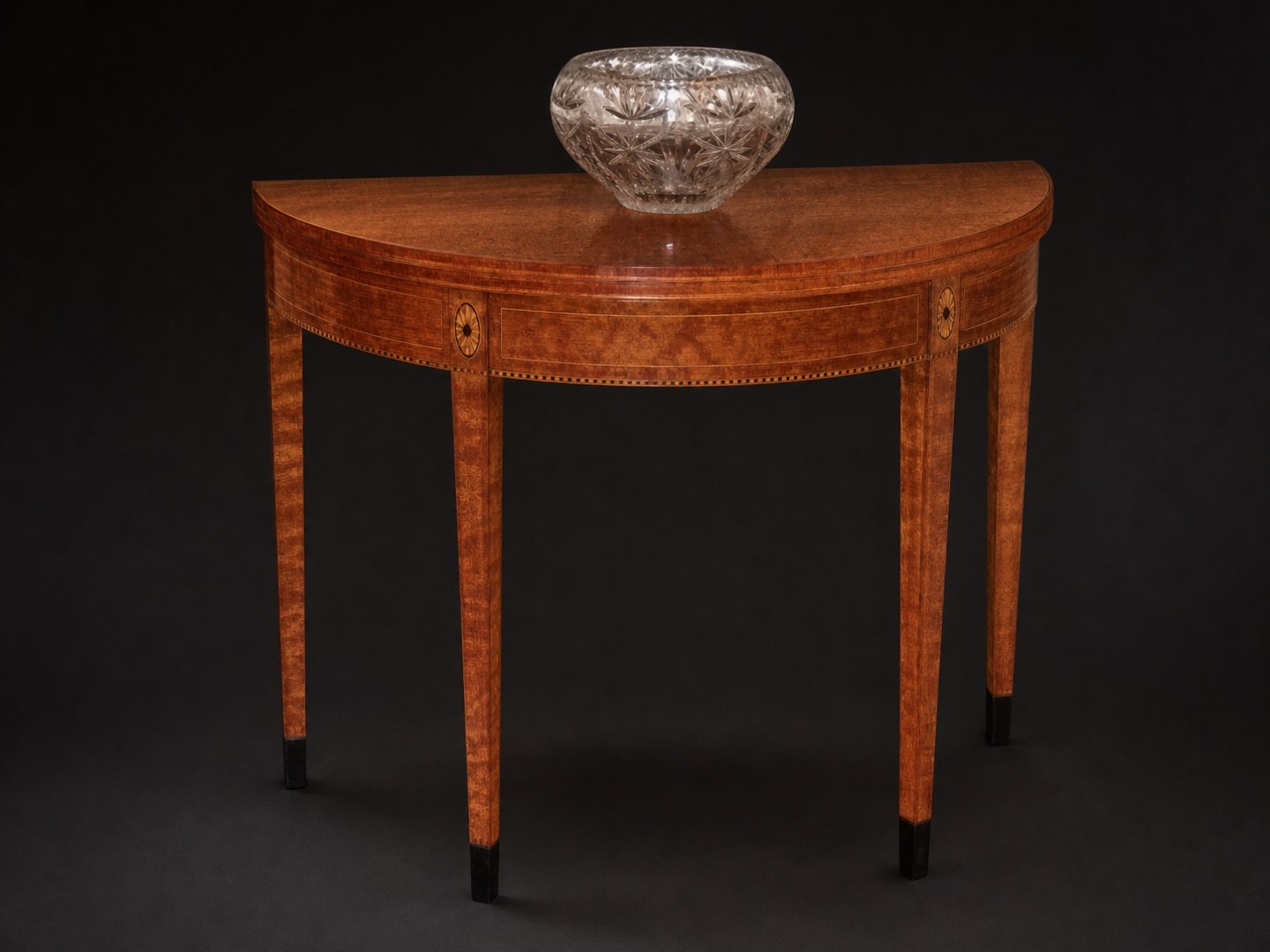 Federal card table in quilted mahogany with a lead crystal bowl on top, on studio black.