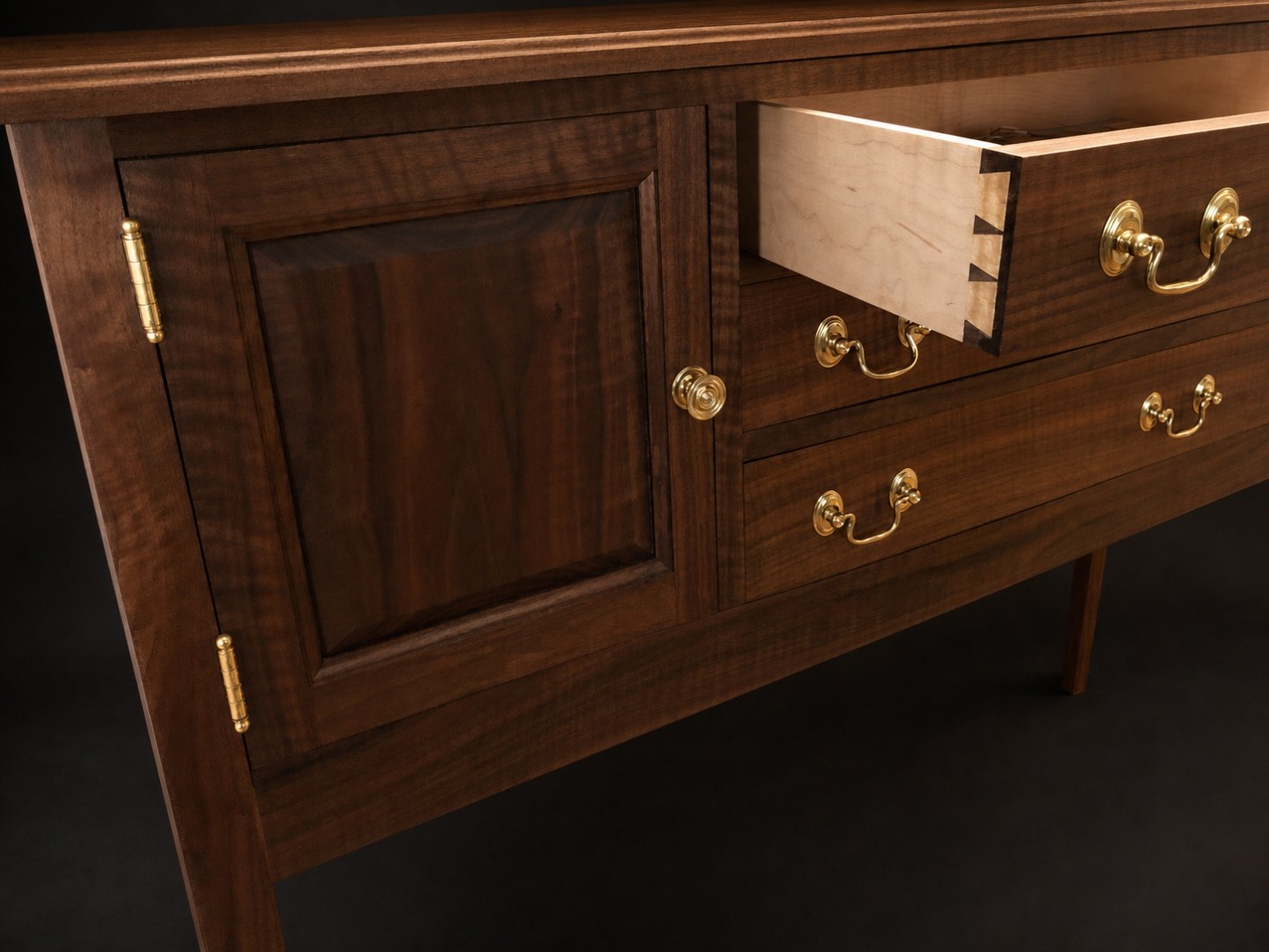 Walnut sideboard open drawer with hand-cut dovetails and tiger maple front, on studio black.
