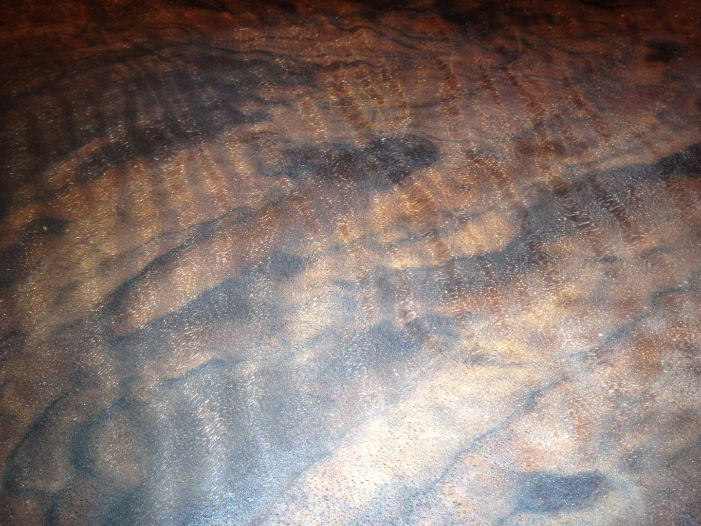 Extreme closeup of curly walnut chatoyance, ribbon figure catching light.