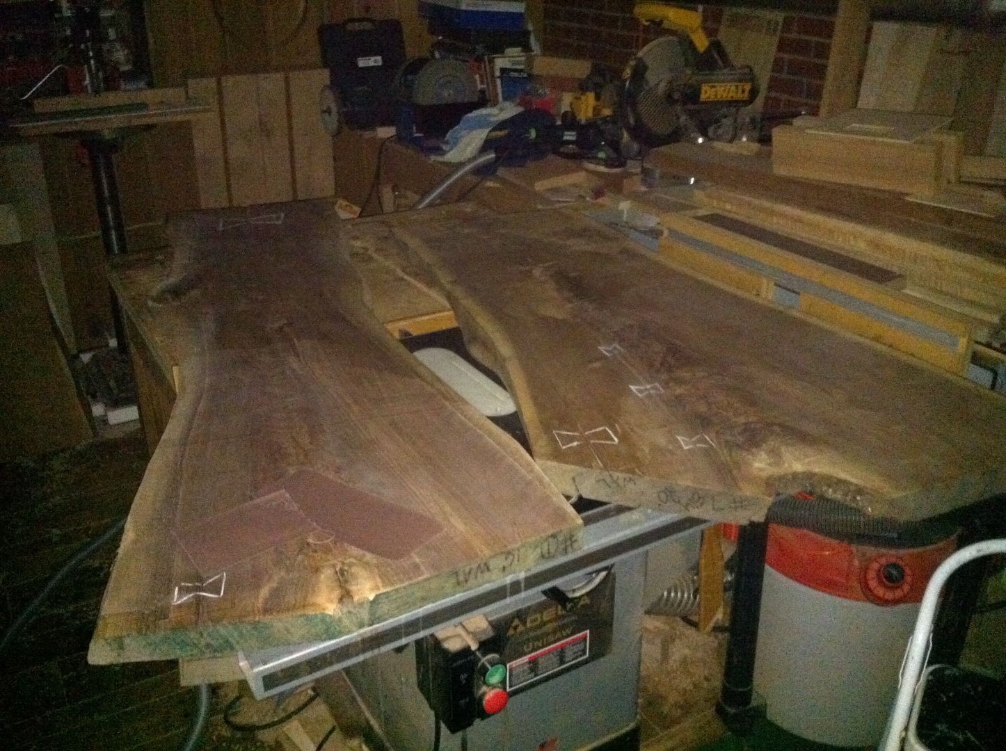 Two live-edge walnut slabs on the table saw with pencil-marked bowtie inlay locations.