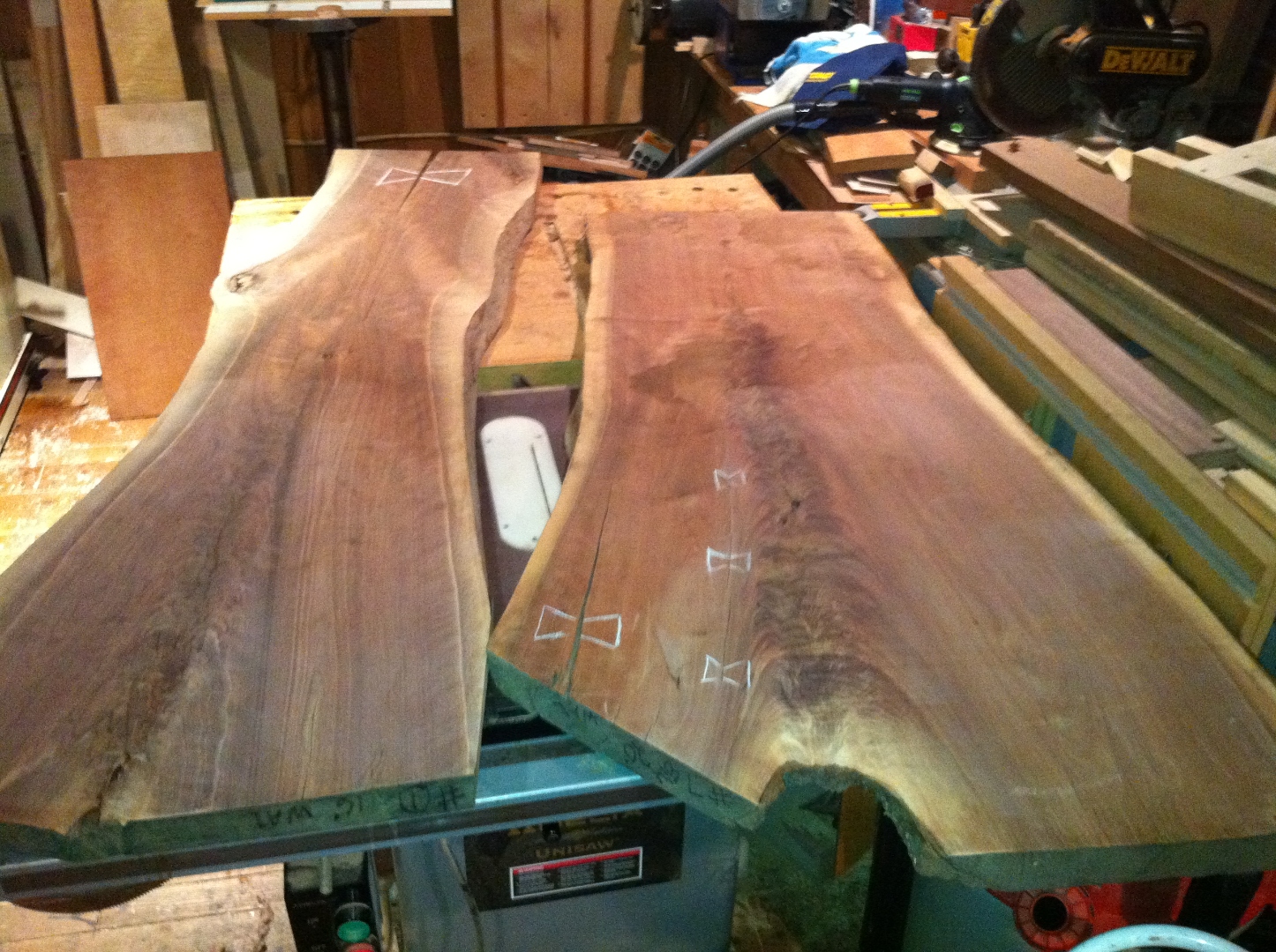 Bookmatched live-edge walnut slabs laid out with chalked bowtie inlays.